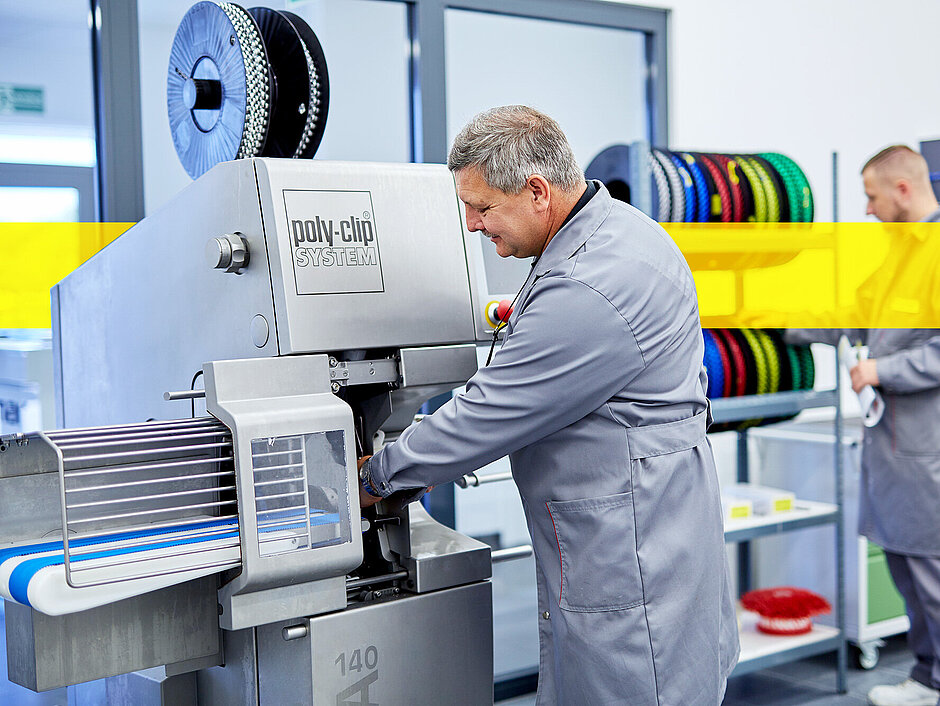 Poly-clip worker in front of machine