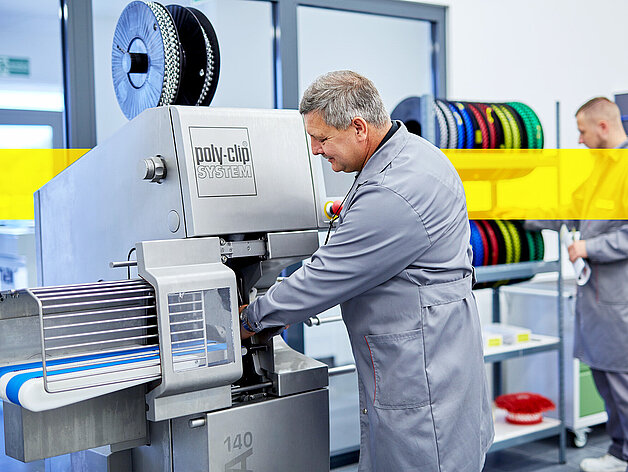 Poly-clip worker in front of machine